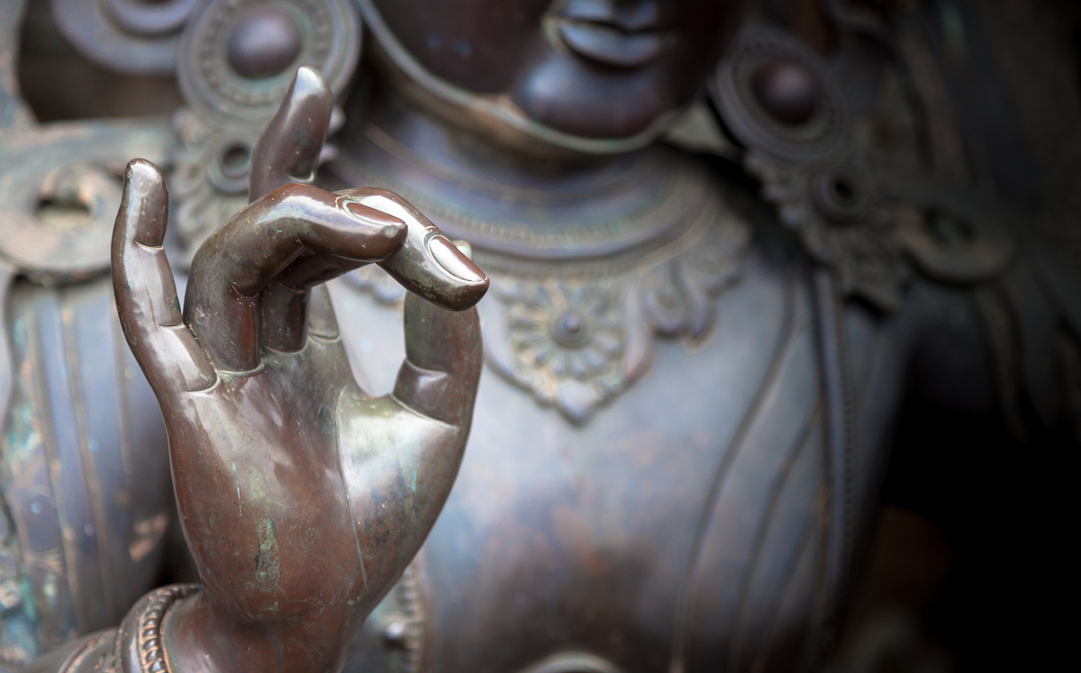 Dettaglio di statua di Buddha con la mano in posizione di Karana Mudra