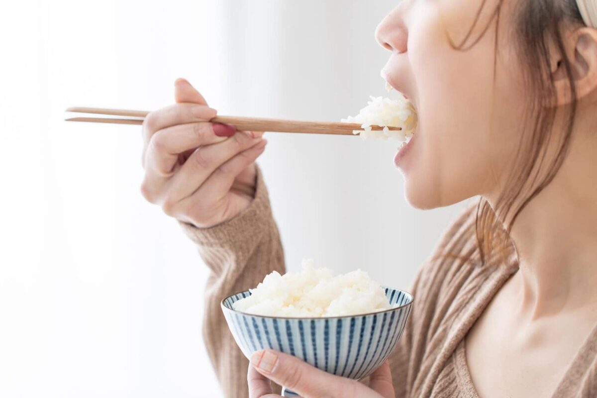 Ragazza che mangia con i bastoncini cinesi per il cibo